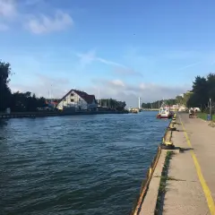 Spacerem nad jeziorem Sarbsko, widać kanał, budynki i łodzie.