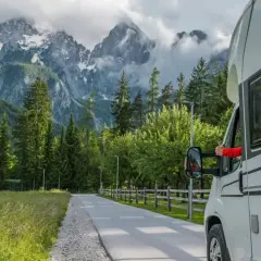 Podróż kamperem po Polsce. Widok na góry i las z okna kampera, ręka pokazuje kciuk w górę.