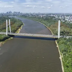 Most Siekierkowski w Warszawie nad Wisłą, z widokiem na panoramę miasta i zielone brzegi.