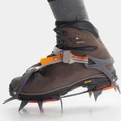 Brązowe buty trekkingowe z zamontowanymi rakami koszykowymi, gotowe na zimowe wyzwania.